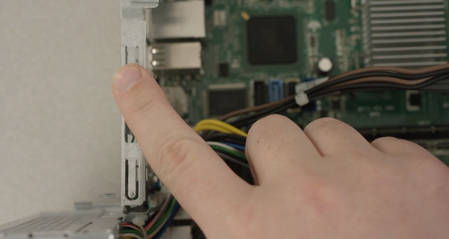 Finger einer Person, die eine unlackierte Metalloberfläche in einem Computer berührt, um statische Elektrizität zu entladen
